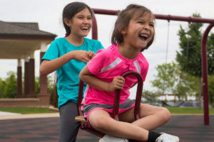 Alexis Bortell, 9, left, and her sister Avery, 6, play on a seesaw at a playground in Littleton, Colorado. Alexis Bortell says she had to stay away from her sister before she used cannabis oil to treat her seizures. (Photo by Nick Swyter/News21.)